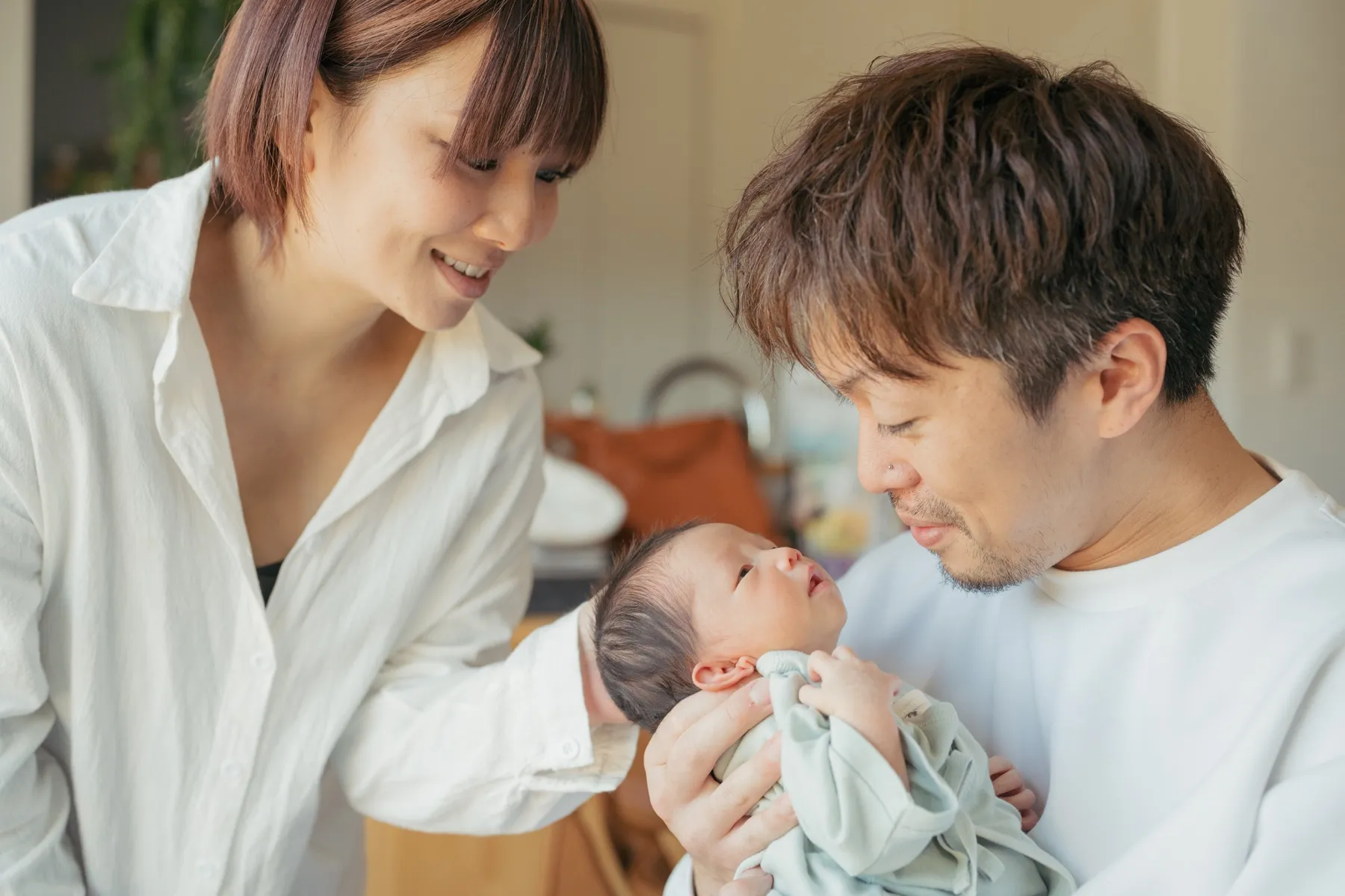 赤ちゃんを両親が見つめるニューボーンフォト