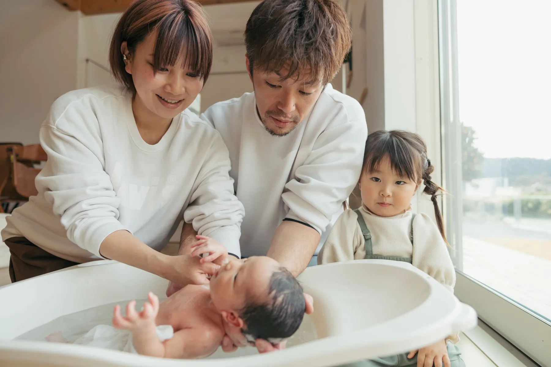 家族で赤ちゃんを沐浴するニューボーンフォト