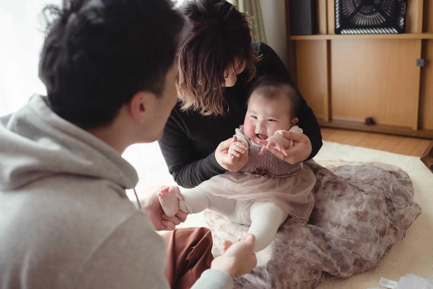 赤ちゃんを囲んで家族が笑い合う写真