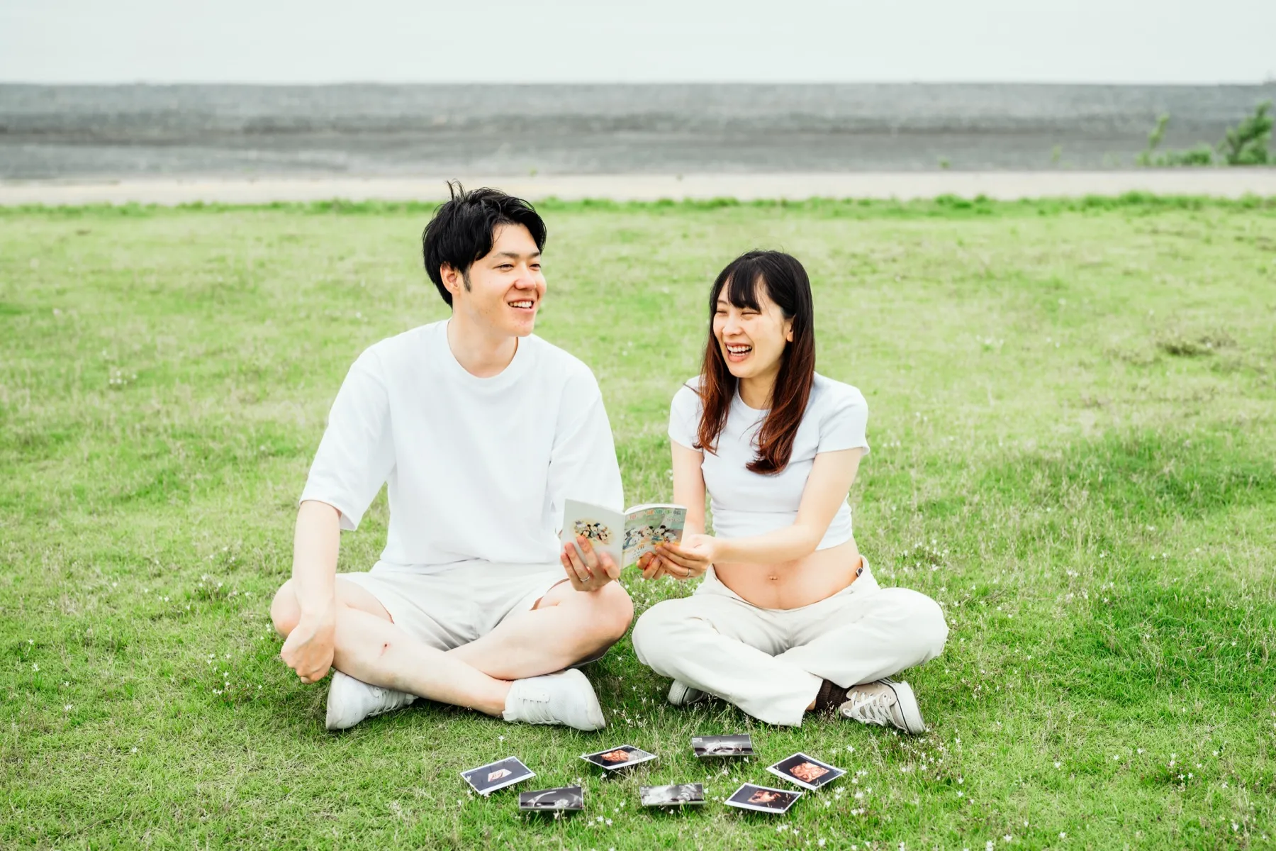 草原で座って過ごす夫婦のマタニティフォト