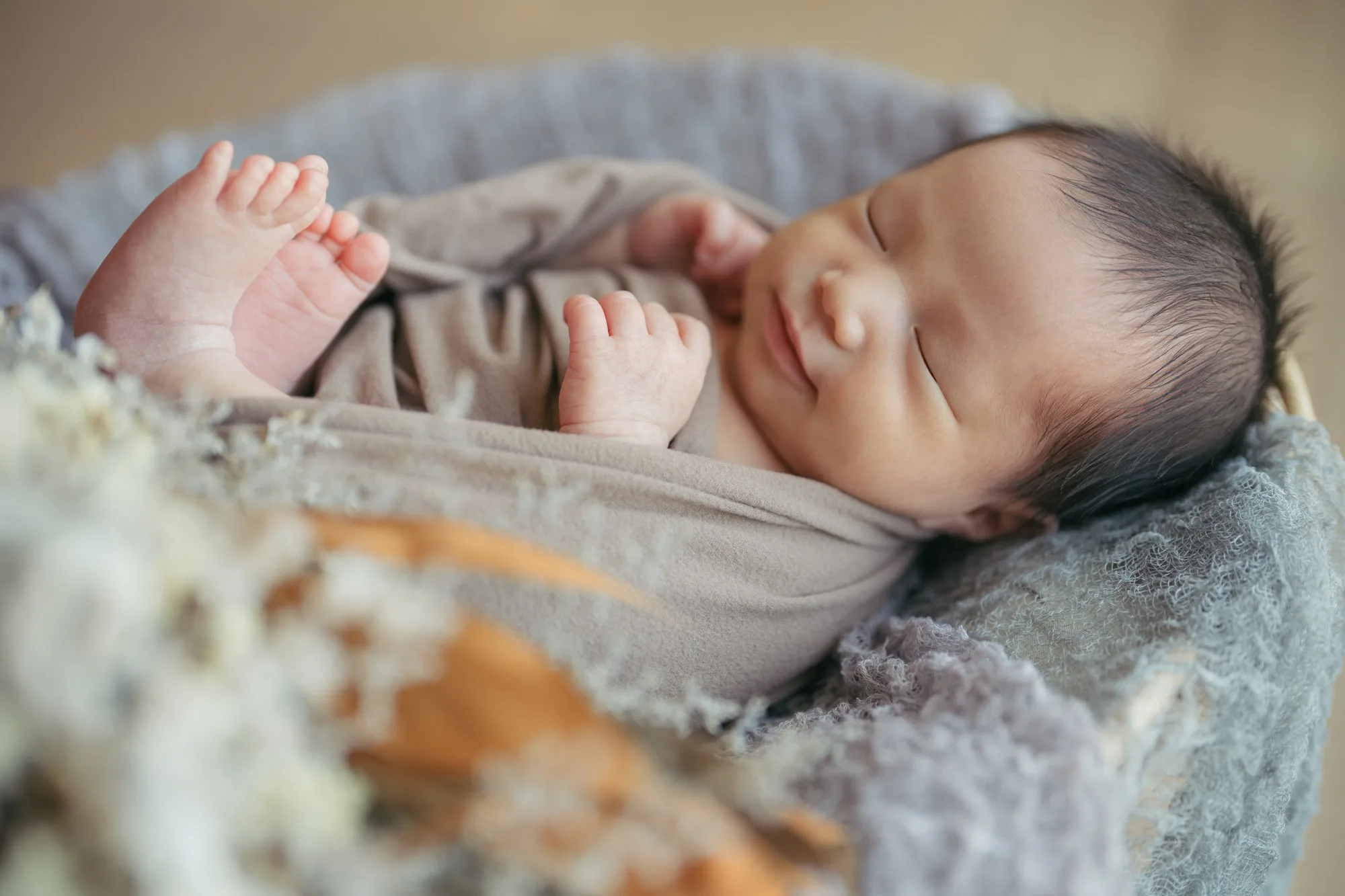 カゴの中で眠り、小さな足をのぞかせる赤ちゃん