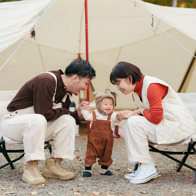 キャンプ場で子どもを囲んで笑い合う家族