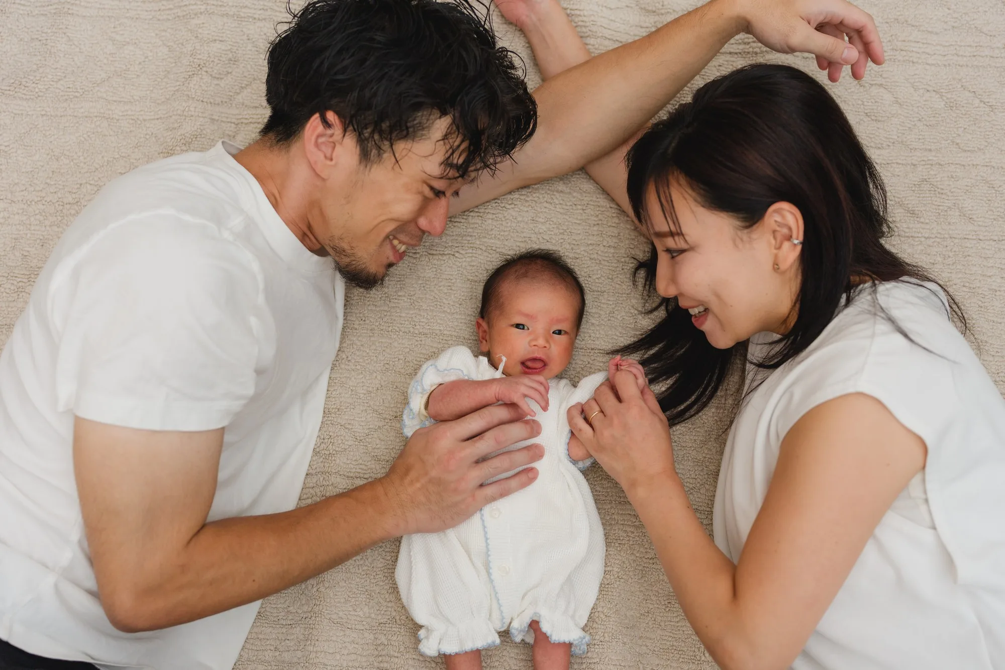 横になった赤ちゃんを、そばで見つめるご両親