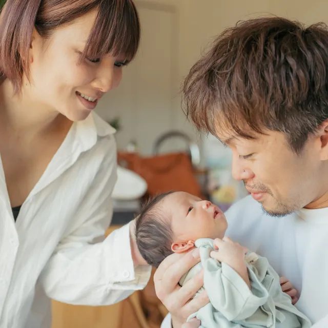 生まれたばかりの赤ちゃんを両親が見つめる家族の時間