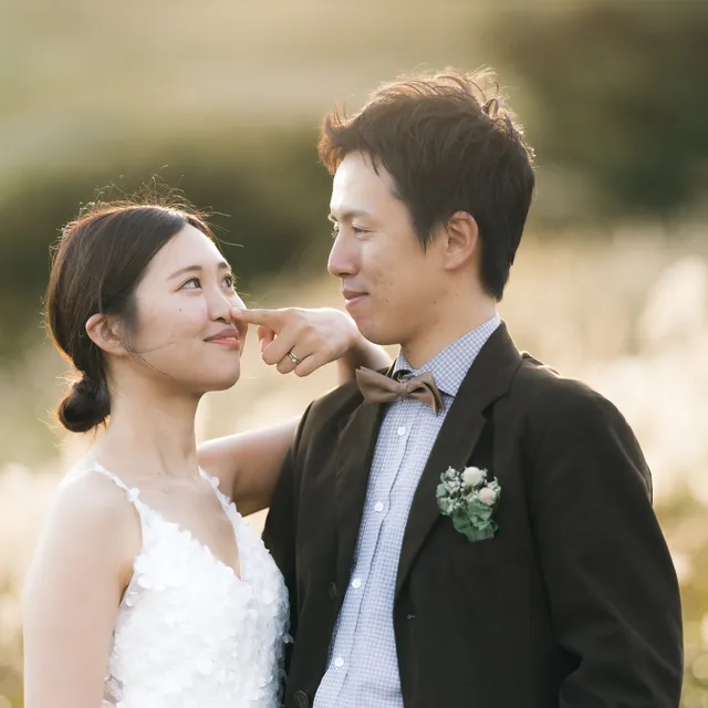 すすき野で見つめ合いながら寄り添う新郎新婦